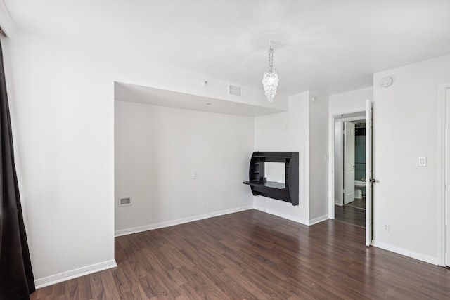 unfurnished living room with dark hardwood / wood-style flooring and an inviting chandelier