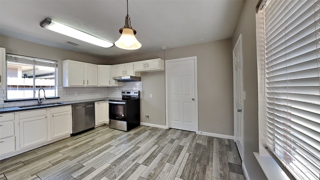 kitchen featuring white cabinets, sink, decorative light fixtures, stainless steel appliances, and light hardwood / wood-style floors