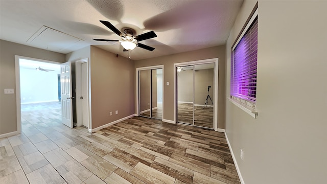 unfurnished bedroom with multiple closets, a textured ceiling, and ceiling fan