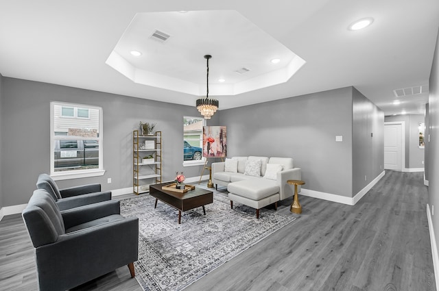 living room with wood-type flooring, a raised ceiling, and a chandelier