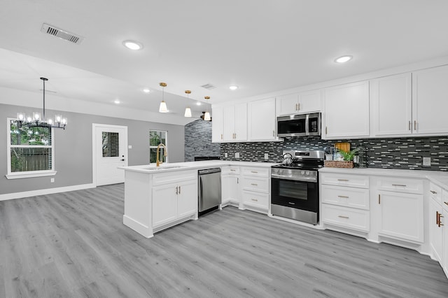 kitchen with stainless steel appliances, kitchen peninsula, hanging light fixtures, and white cabinets