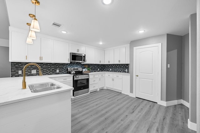 kitchen with pendant lighting, light hardwood / wood-style flooring, sink, stainless steel appliances, and white cabinets