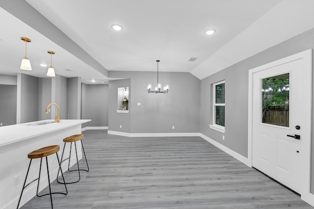 kitchen featuring hanging light fixtures, sink, and light wood-type flooring