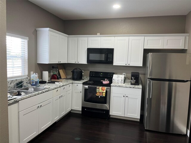 kitchen with sink, stainless steel appliances, white cabinets, light stone counters, and dark hardwood / wood-style floors