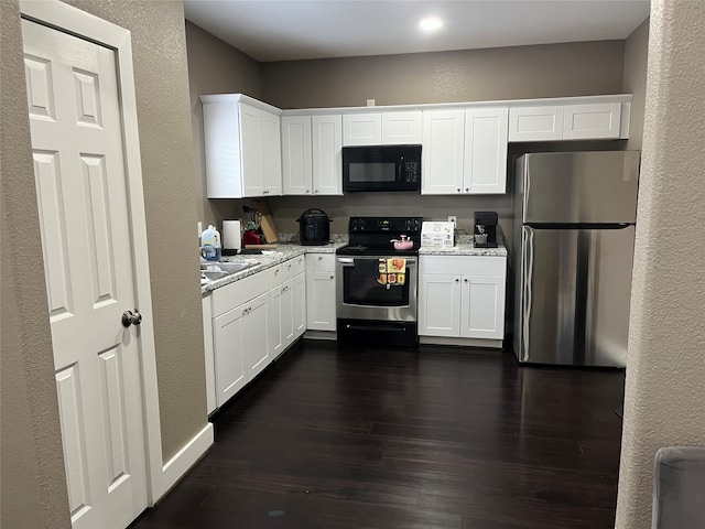 kitchen with light stone countertops, white cabinets, stainless steel appliances, and dark hardwood / wood-style flooring