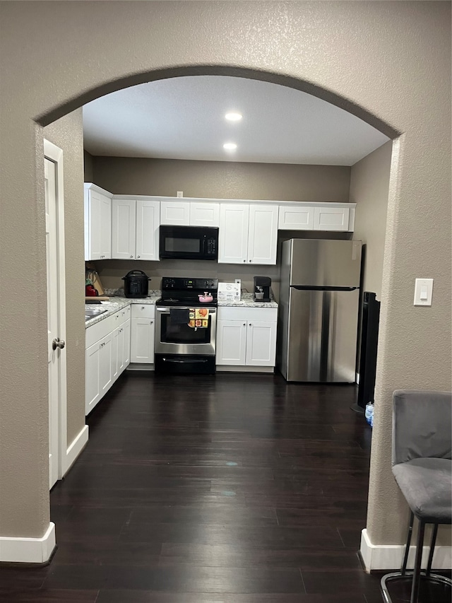 kitchen with white cabinetry, stainless steel appliances, and dark hardwood / wood-style flooring