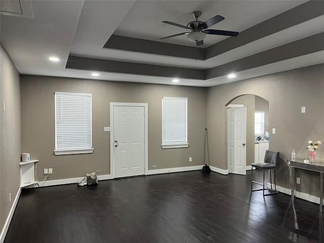 miscellaneous room with ceiling fan, a tray ceiling, and dark hardwood / wood-style flooring