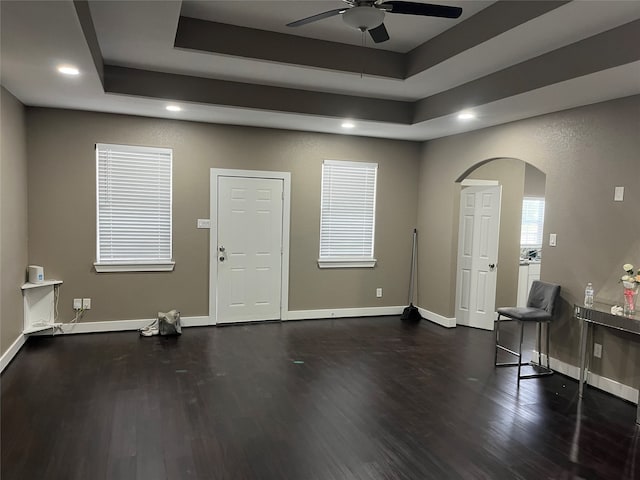 interior space with dark wood-type flooring and a tray ceiling