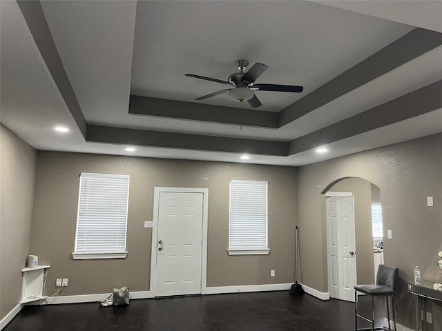 unfurnished room with a raised ceiling, ceiling fan, and dark wood-type flooring