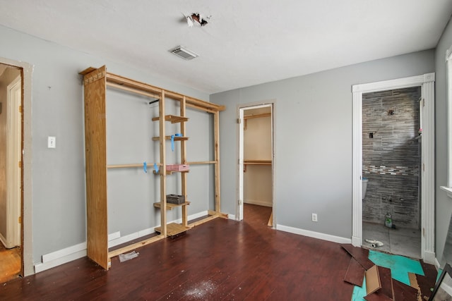 unfurnished bedroom with a walk in closet, dark hardwood / wood-style flooring, and a closet