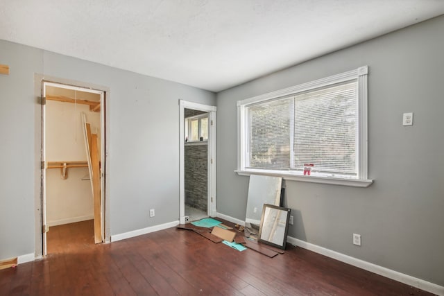 unfurnished bedroom featuring dark hardwood / wood-style flooring, a spacious closet, and a closet