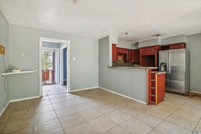 kitchen with stainless steel fridge, light tile patterned flooring, kitchen peninsula, and a textured ceiling