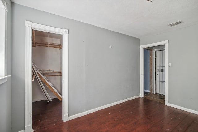 unfurnished bedroom with dark hardwood / wood-style flooring and a closet