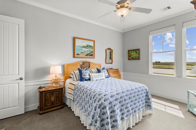 carpeted bedroom featuring wood walls, ornamental molding, and ceiling fan