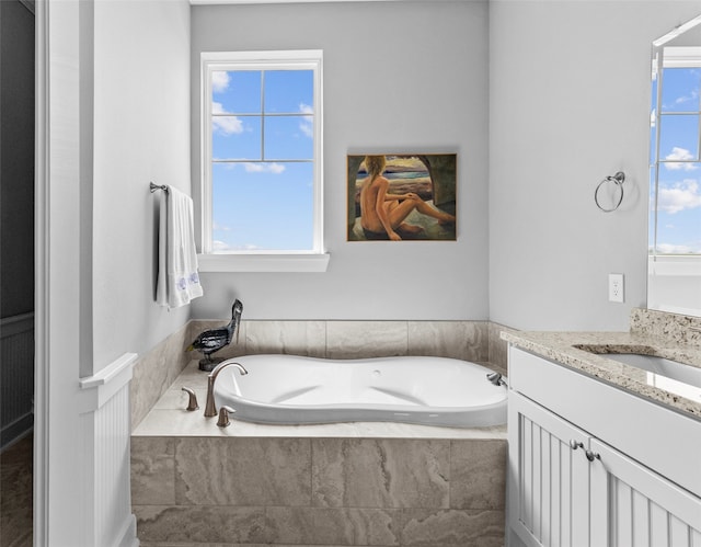 bathroom with tiled tub and vanity
