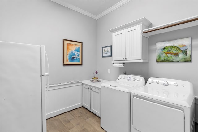 clothes washing area featuring ornamental molding, washer and clothes dryer, light hardwood / wood-style floors, and cabinets