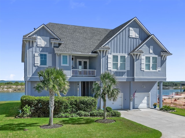 view of front of property featuring a water view, a front lawn, a balcony, and a garage