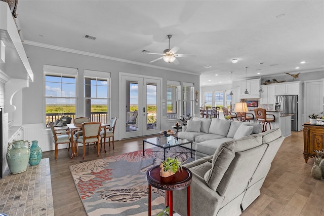 living room with crown molding, ceiling fan, hardwood / wood-style floors, and french doors