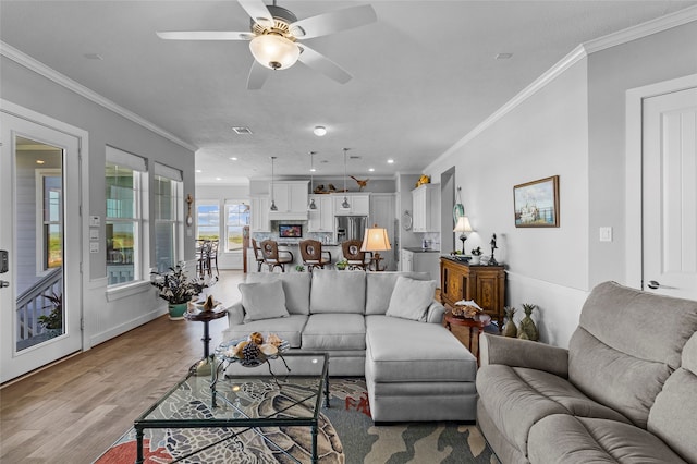living room with light hardwood / wood-style floors, ornamental molding, and ceiling fan