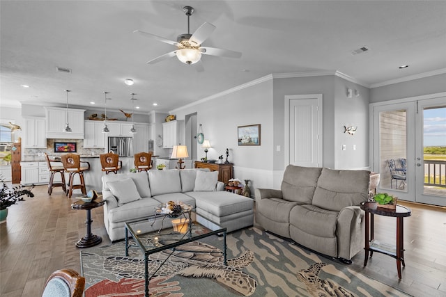 living room with ceiling fan, light wood-type flooring, crown molding, and french doors