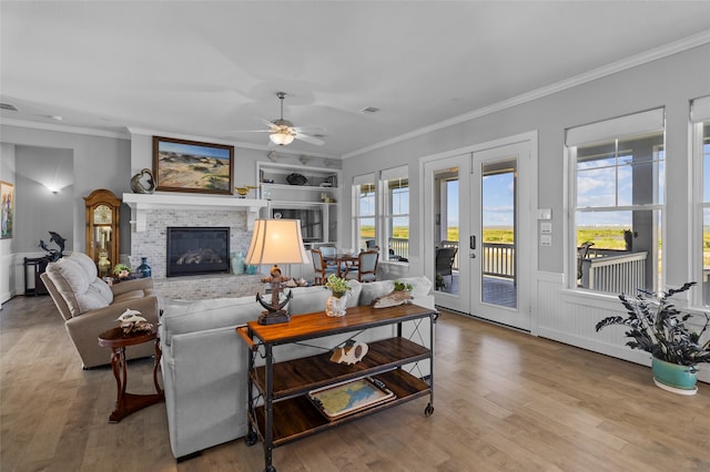 living room with ceiling fan, hardwood / wood-style flooring, a brick fireplace, and french doors