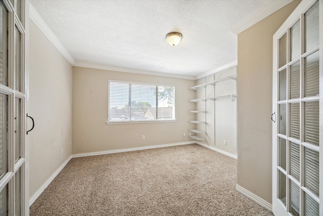 carpeted spare room with french doors, ornamental molding, and a textured ceiling