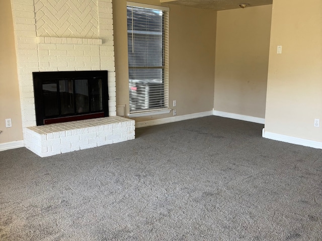 unfurnished living room with a brick fireplace and dark carpet