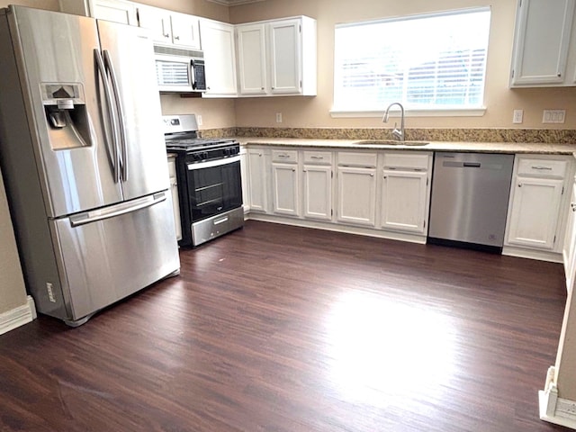 kitchen with appliances with stainless steel finishes, dark wood-type flooring, white cabinetry, sink, and crown molding