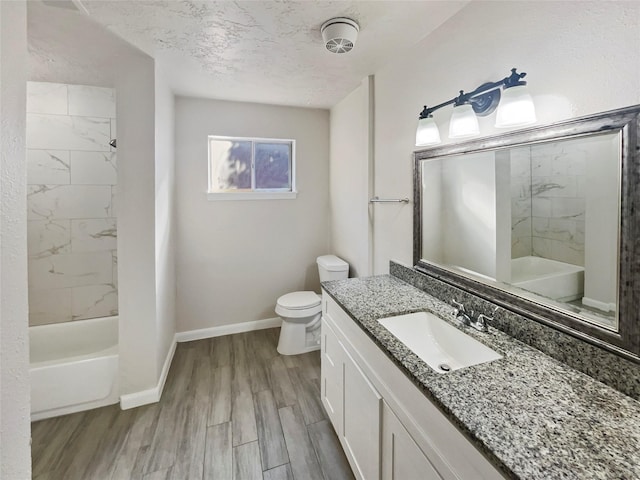 bathroom with wood finished floors, a textured ceiling, vanity, baseboards, and toilet