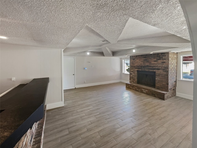 unfurnished living room with a textured ceiling, light hardwood / wood-style flooring, and a healthy amount of sunlight