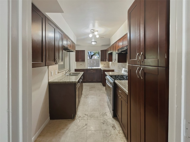 kitchen featuring stainless steel gas range oven, light stone counters, and sink