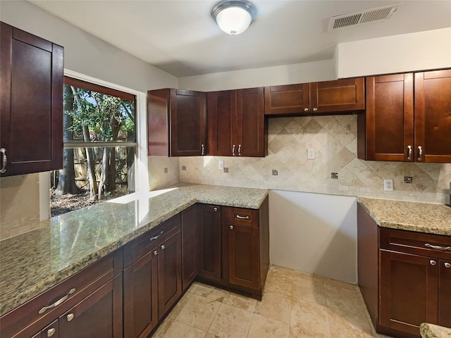 kitchen featuring tasteful backsplash and light stone counters