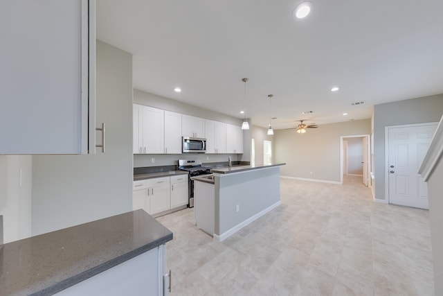 kitchen with ceiling fan, white cabinets, hanging light fixtures, a kitchen island with sink, and appliances with stainless steel finishes