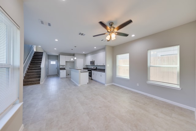 kitchen featuring ceiling fan, decorative light fixtures, white cabinetry, stainless steel appliances, and a center island