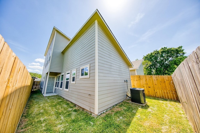 back of house featuring cooling unit and a lawn