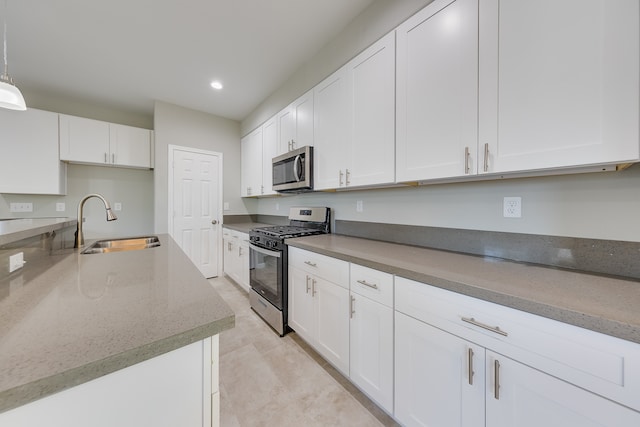 kitchen with hanging light fixtures, appliances with stainless steel finishes, sink, and white cabinetry