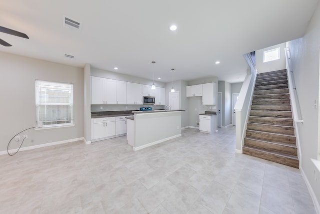 kitchen featuring a center island with sink, white cabinetry, pendant lighting, and ceiling fan