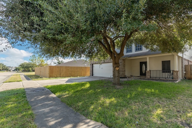 view of property hidden behind natural elements featuring a front lawn, covered porch, and a garage