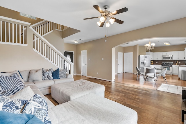 living room featuring wood-type flooring and ceiling fan with notable chandelier