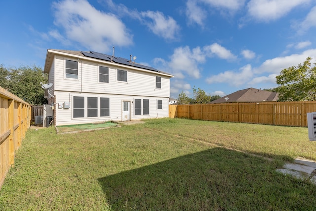 back of house with central air condition unit and a lawn