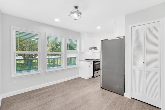 kitchen with appliances with stainless steel finishes, backsplash, light hardwood / wood-style floors, and white cabinets