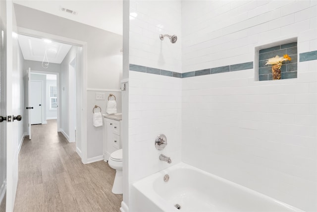 full bathroom with vanity, hardwood / wood-style flooring, tiled shower / bath combo, and toilet