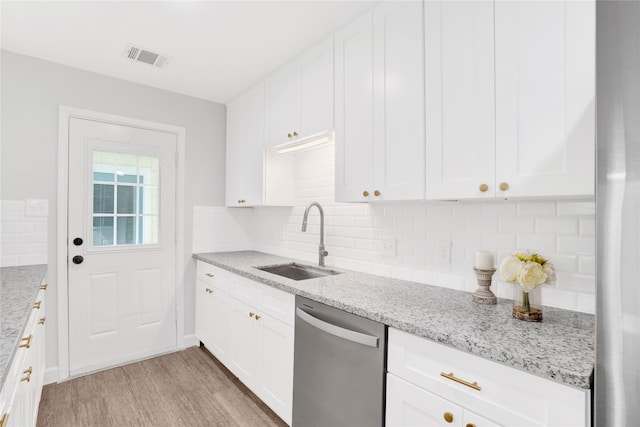 kitchen featuring sink, white cabinetry, stainless steel dishwasher, and light hardwood / wood-style flooring