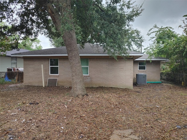 back of property featuring central AC, brick siding, and fence