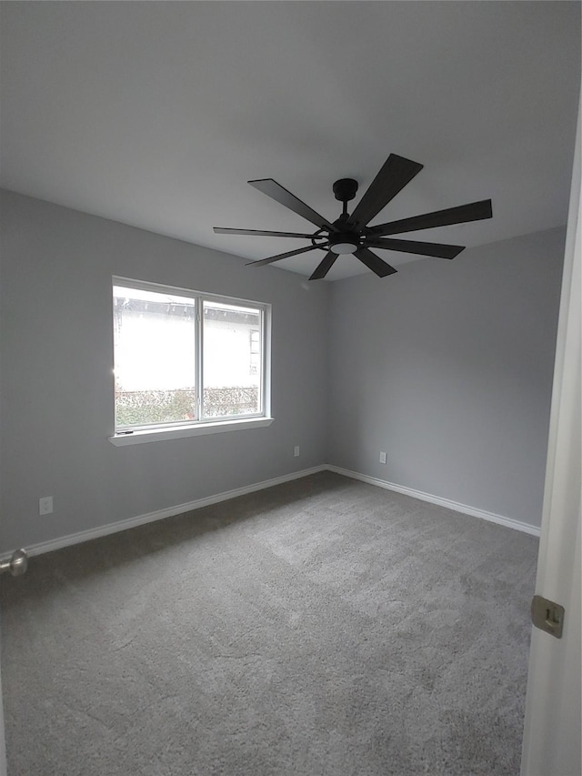 carpeted empty room featuring ceiling fan and baseboards