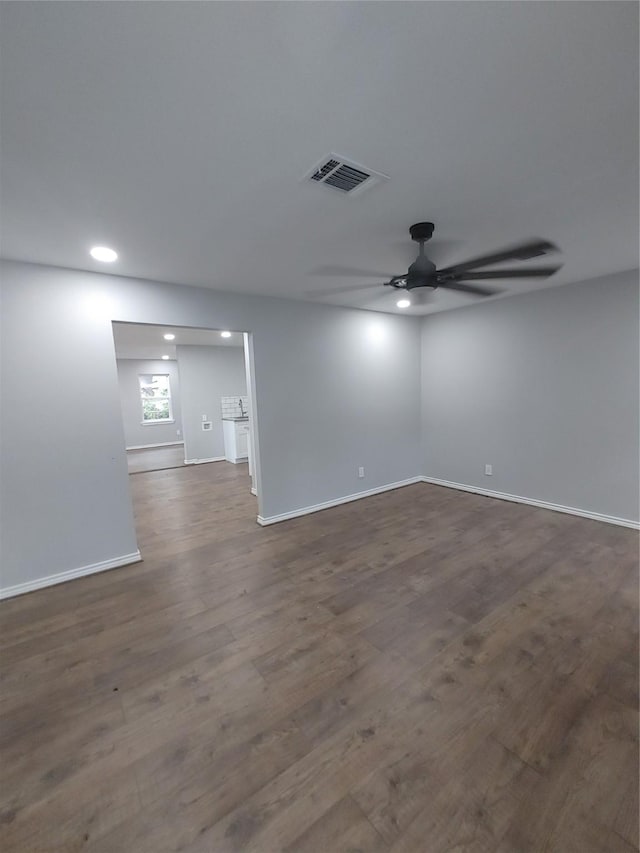 unfurnished room with dark wood-style floors, ceiling fan, visible vents, and baseboards