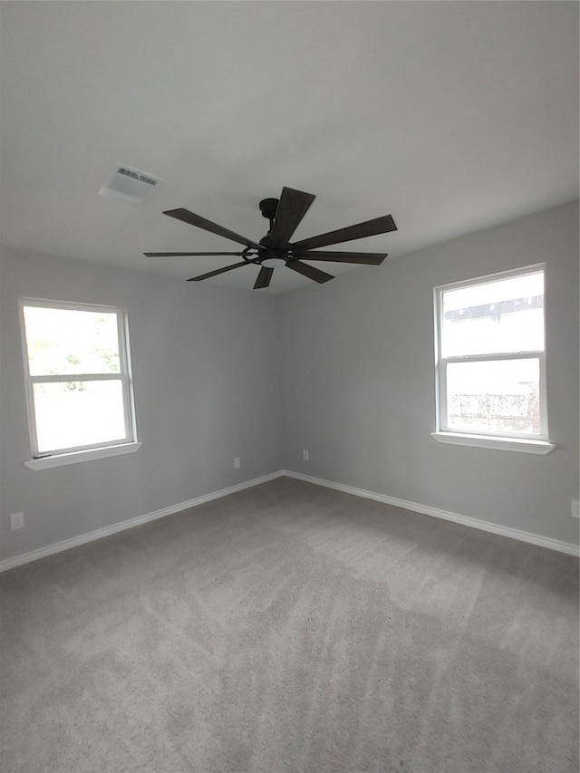 unfurnished room featuring baseboards, visible vents, ceiling fan, and light colored carpet