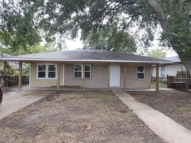 ranch-style home with a shingled roof, brick siding, and fence