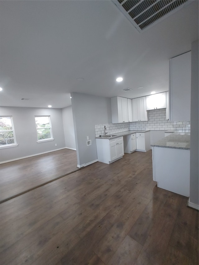 kitchen with backsplash, dark hardwood / wood-style flooring, white cabinetry, sink, and light stone counters