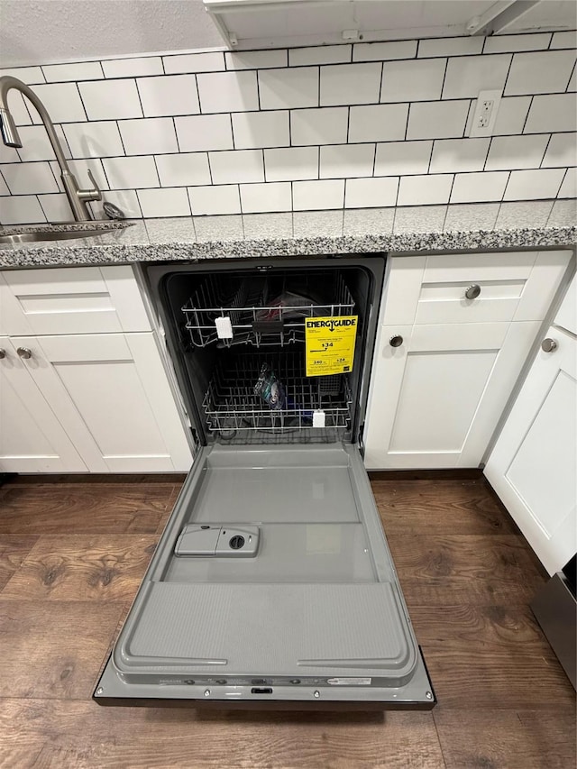 details with dark wood-type flooring, white cabinets, dishwashing machine, and light stone countertops